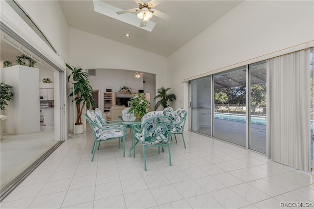 tiled dining area with ceiling fan and high vaulted ceiling