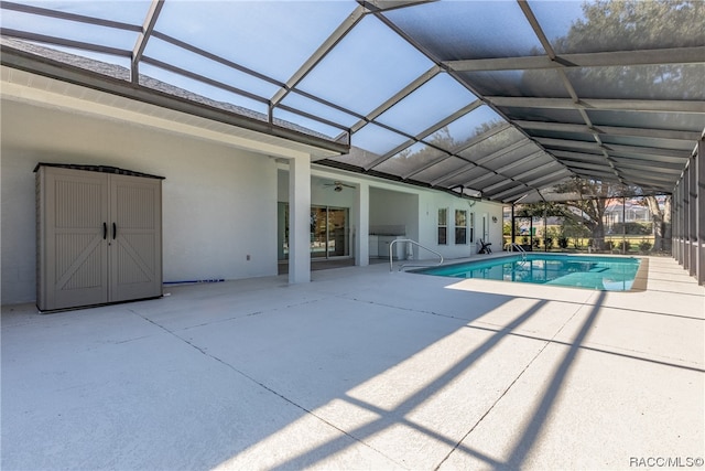 view of swimming pool featuring glass enclosure, ceiling fan, and a patio