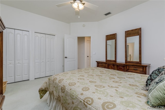 bedroom featuring light carpet, two closets, and ceiling fan