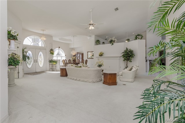 living room with french doors, ceiling fan with notable chandelier, light colored carpet, and a high ceiling