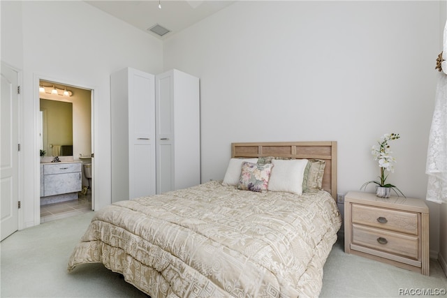 carpeted bedroom with ensuite bathroom and a closet