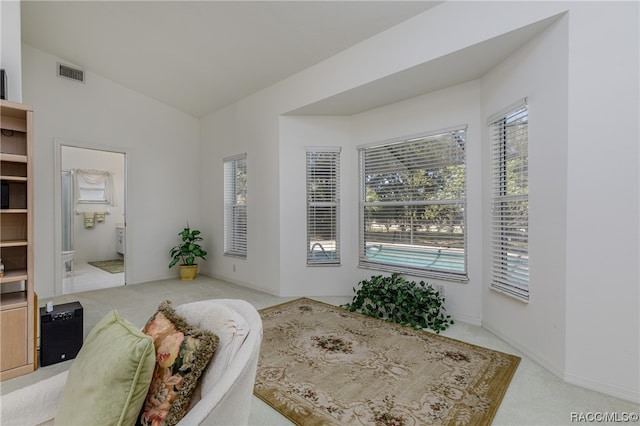 bedroom featuring ensuite bathroom, light carpet, and lofted ceiling