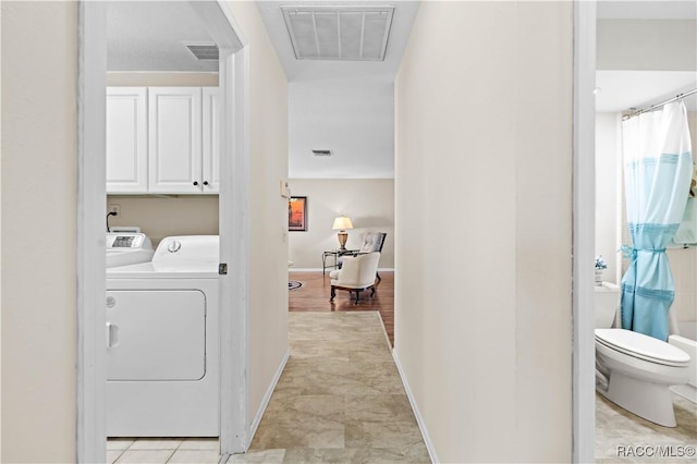 clothes washing area featuring cabinets, light tile patterned flooring, and separate washer and dryer