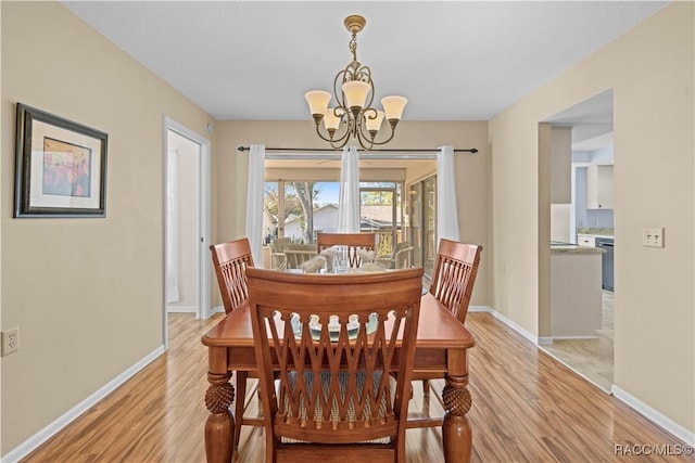 dining space with a notable chandelier and light hardwood / wood-style flooring