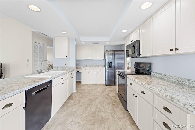 kitchen with white cabinets, a tray ceiling, sink, and black appliances