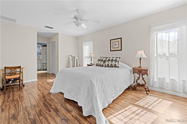 bedroom featuring ceiling fan, hardwood / wood-style floors, and multiple windows