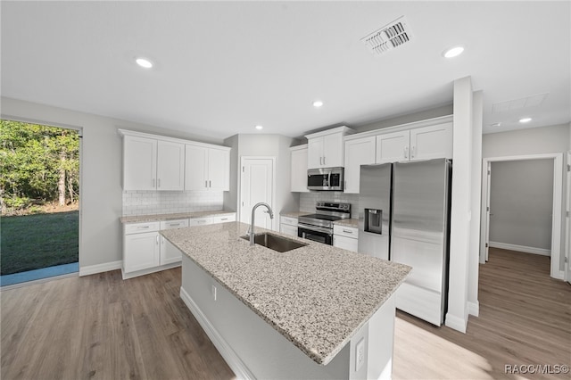 kitchen featuring sink, an island with sink, light hardwood / wood-style floors, white cabinetry, and stainless steel appliances