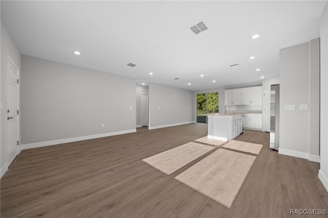 unfurnished living room with wood-type flooring and sink