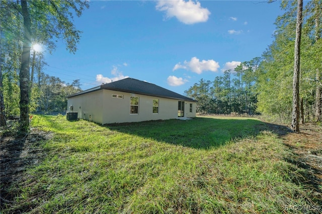 view of side of property with cooling unit and a lawn