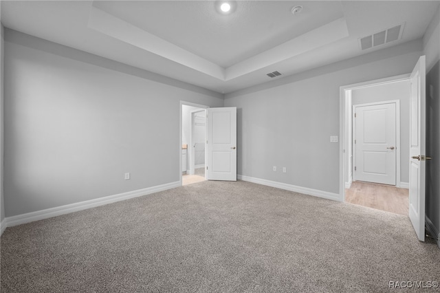 unfurnished bedroom with carpet flooring and a raised ceiling