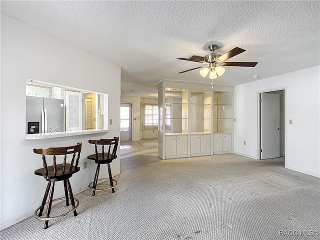 carpeted living room featuring ceiling fan and a textured ceiling