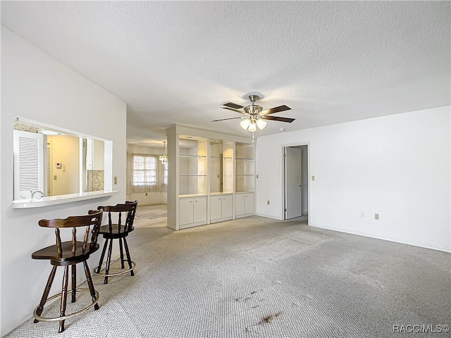 interior space featuring light carpet, a textured ceiling, and ceiling fan