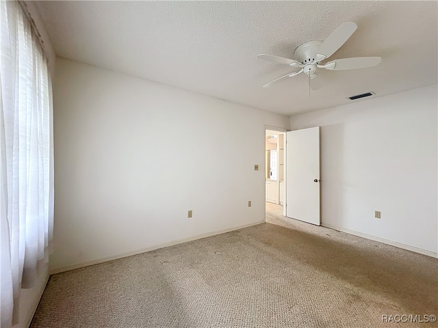 unfurnished room with ceiling fan, carpet floors, and a textured ceiling