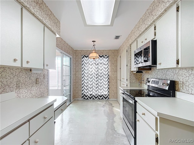 kitchen with appliances with stainless steel finishes, white cabinetry, and hanging light fixtures