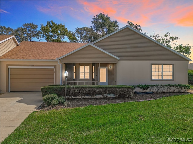 ranch-style home with a yard, covered porch, and a garage