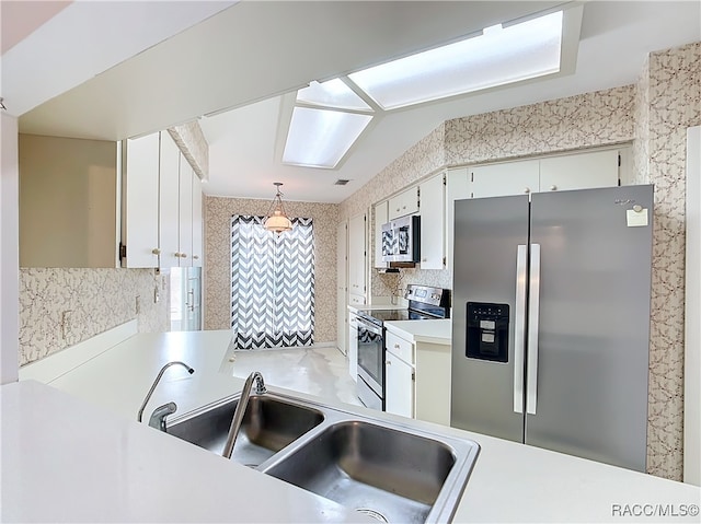 kitchen featuring sink, hanging light fixtures, backsplash, white cabinets, and appliances with stainless steel finishes