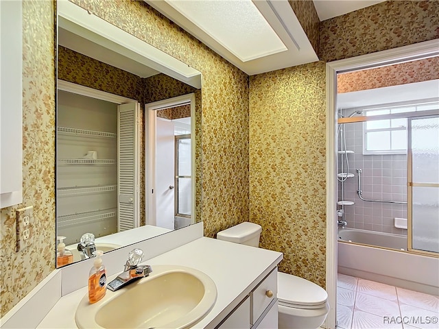 full bathroom with tile patterned floors, vanity, toilet, and bath / shower combo with glass door