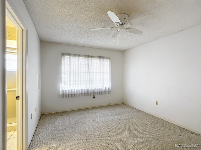 carpeted empty room featuring ceiling fan and a textured ceiling