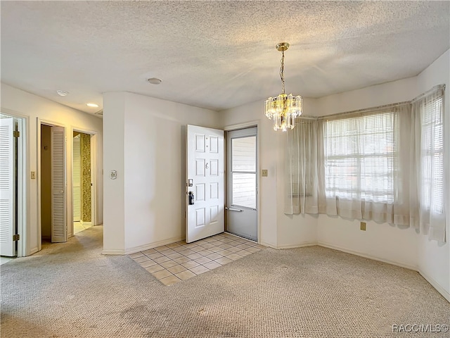 carpeted foyer entrance featuring a chandelier and a textured ceiling