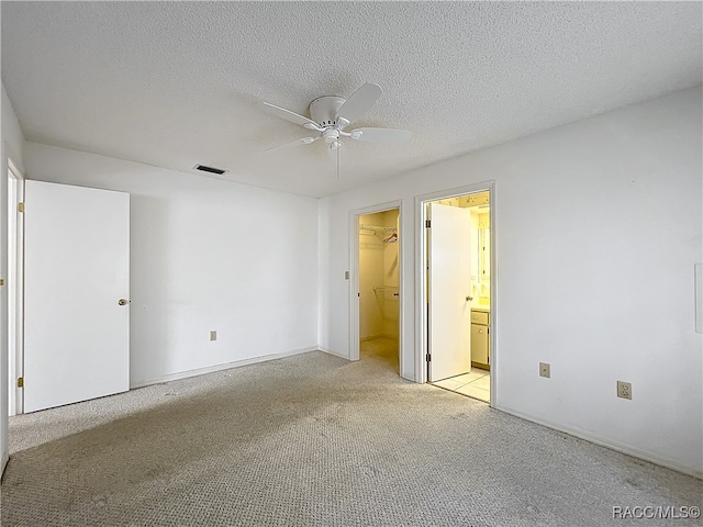 empty room featuring light carpet, ceiling fan, and a textured ceiling