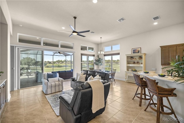 tiled living room with ceiling fan with notable chandelier