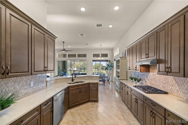 kitchen with ceiling fan with notable chandelier, sink, hanging light fixtures, decorative backsplash, and appliances with stainless steel finishes