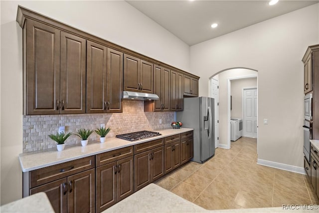 kitchen featuring washer and dryer, appliances with stainless steel finishes, tasteful backsplash, and dark brown cabinets