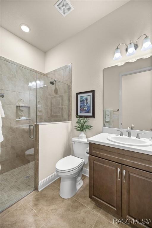 bathroom featuring tile patterned flooring, toilet, vanity, and walk in shower