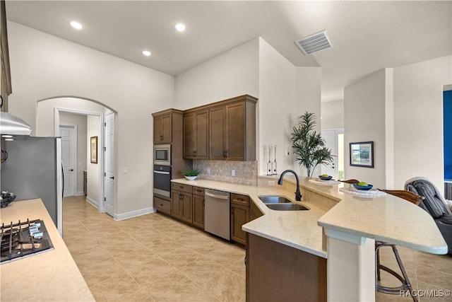 kitchen featuring a breakfast bar, backsplash, sink, kitchen peninsula, and stainless steel appliances