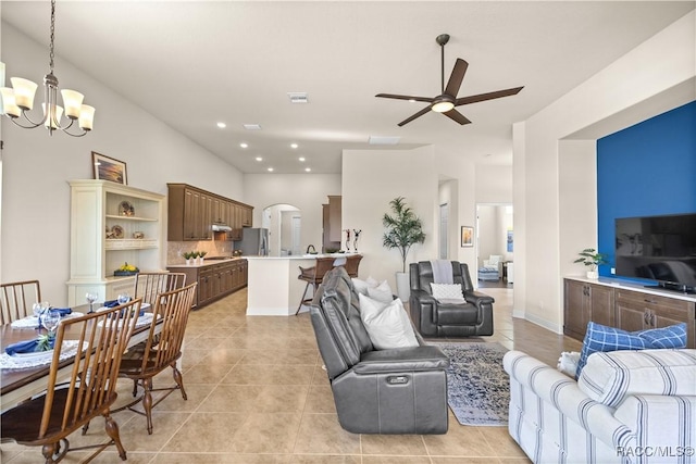 tiled living room with ceiling fan with notable chandelier