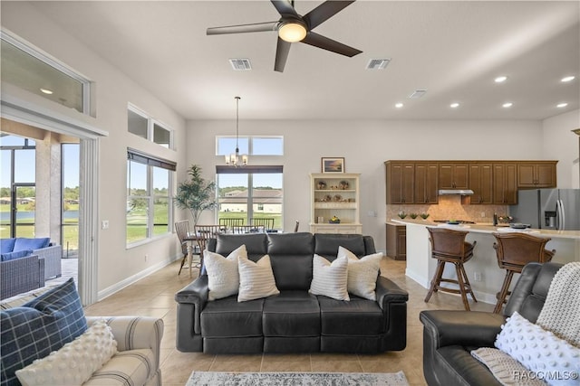 living room with ceiling fan with notable chandelier, light tile patterned floors, and a wealth of natural light