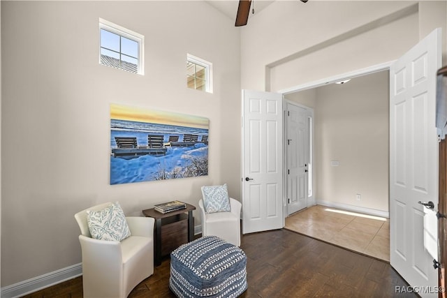 living area featuring ceiling fan, a towering ceiling, and dark hardwood / wood-style floors