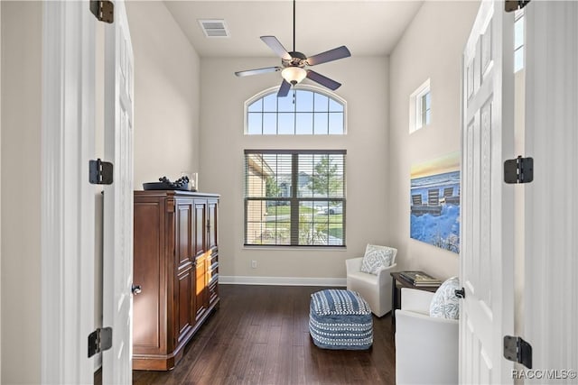 sitting room with ceiling fan and dark wood-type flooring