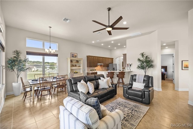 living room with ceiling fan with notable chandelier, light tile patterned floors, and a high ceiling