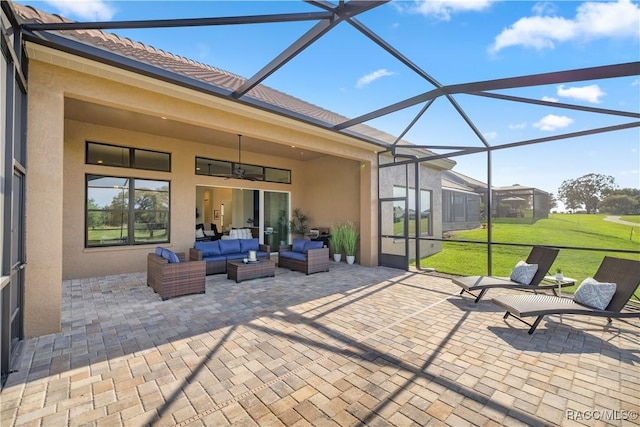 view of patio featuring glass enclosure, an outdoor living space, and ceiling fan