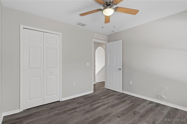 unfurnished bedroom with dark hardwood / wood-style flooring, a closet, and ceiling fan