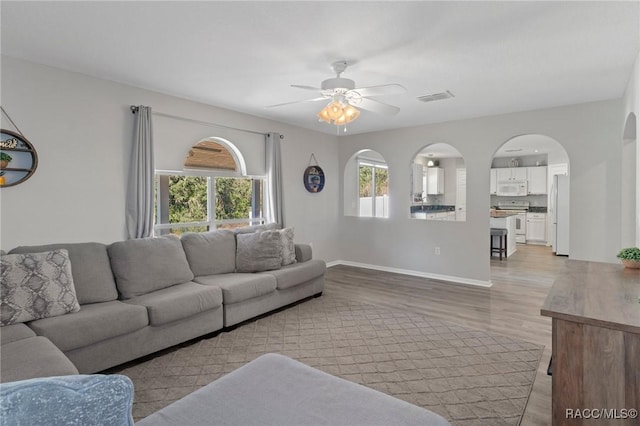 living room with light wood-type flooring, plenty of natural light, and ceiling fan