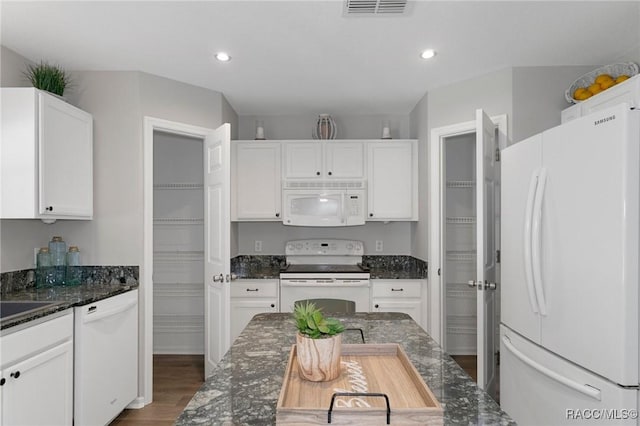 kitchen with dark stone countertops, white cabinetry, white appliances, and hardwood / wood-style flooring