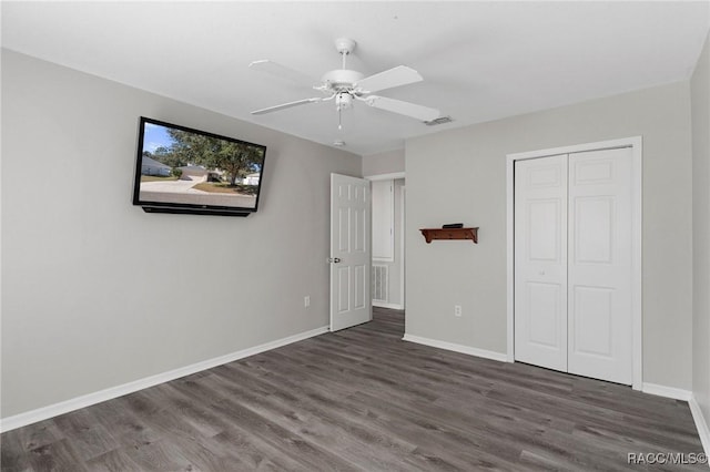 unfurnished bedroom with ceiling fan, dark hardwood / wood-style floors, and a closet