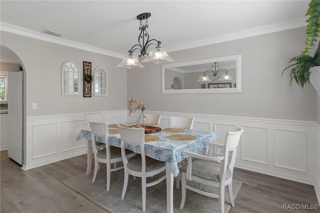 dining room with hardwood / wood-style flooring, crown molding, and a chandelier