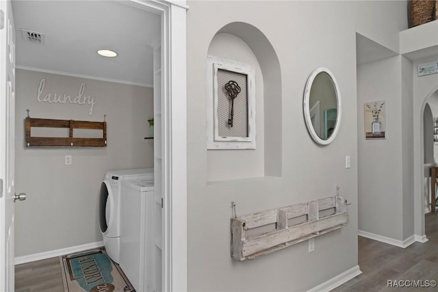 laundry room with crown molding, dark hardwood / wood-style flooring, and washer and dryer