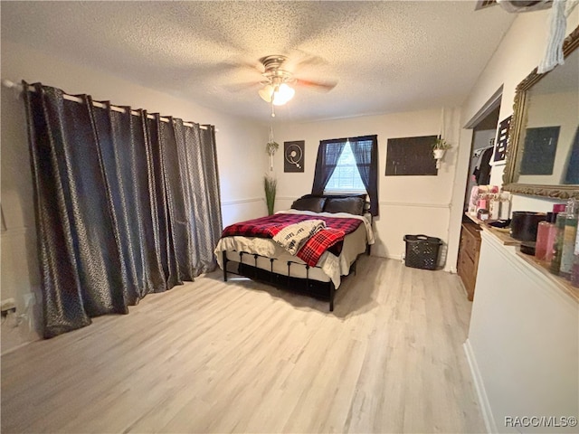 bedroom featuring ceiling fan, a textured ceiling, and light wood-type flooring