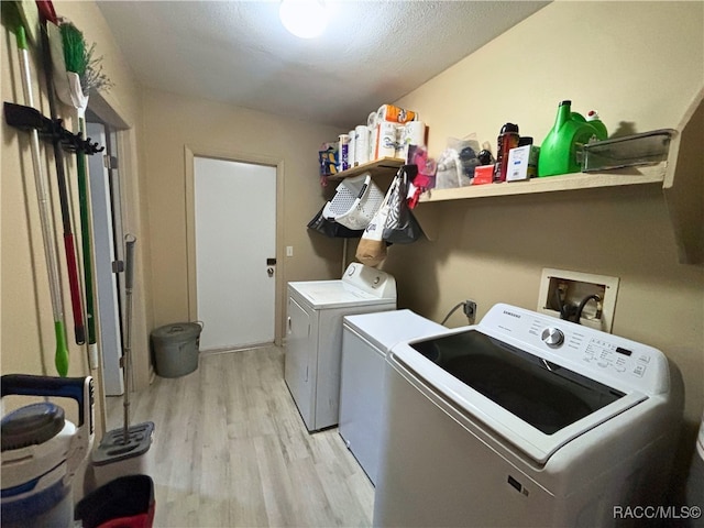 clothes washing area featuring washing machine and clothes dryer and light hardwood / wood-style floors