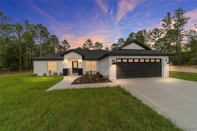 view of front of house with an attached garage, driveway, a front lawn, and a shingled roof