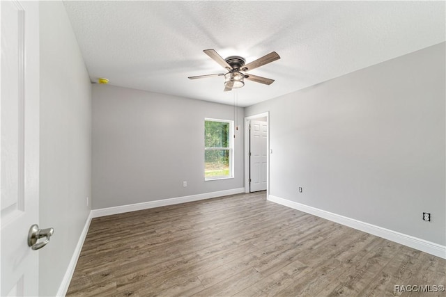 spare room with a ceiling fan, wood finished floors, baseboards, and a textured ceiling
