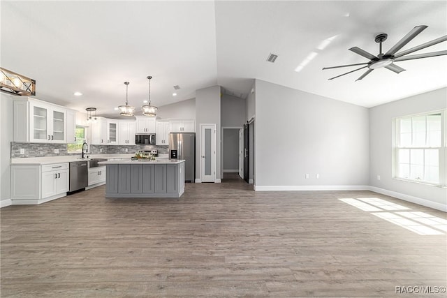 kitchen featuring appliances with stainless steel finishes, open floor plan, lofted ceiling, and a center island
