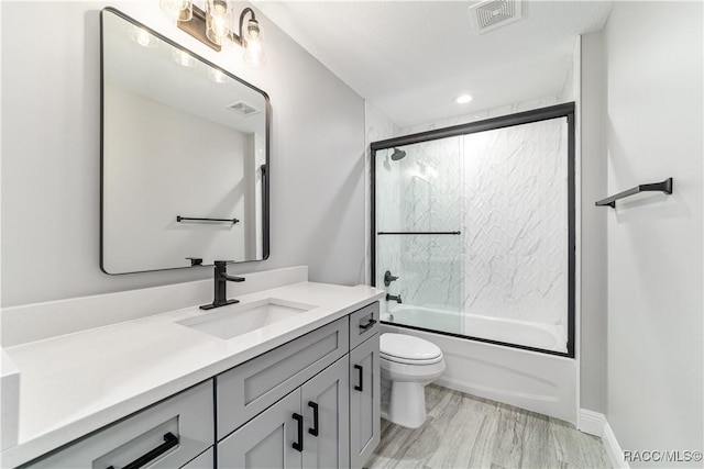 full bath featuring vanity, toilet, and combined bath / shower with glass door