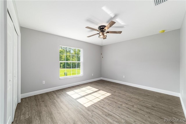 unfurnished bedroom featuring wood finished floors, baseboards, a closet, and ceiling fan
