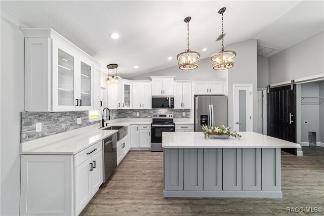 kitchen featuring stainless steel appliances, a sink, a chandelier, backsplash, and lofted ceiling