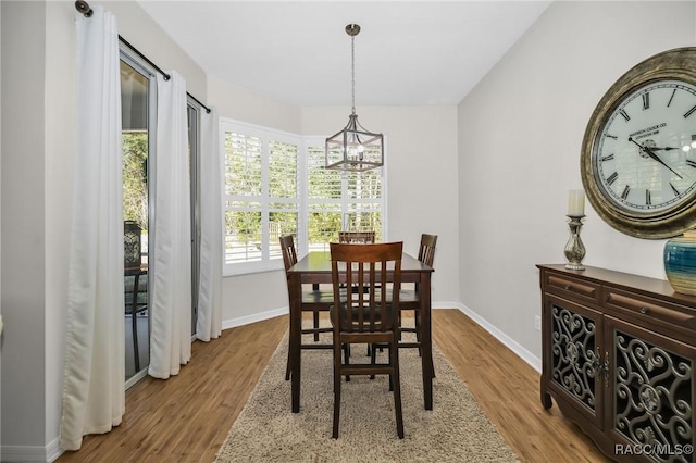 dining area featuring an inviting chandelier, wood finished floors, and baseboards